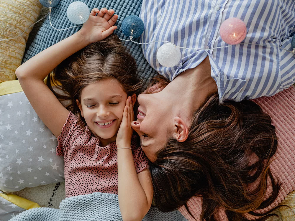 The mother has a gentle smile on her face, and the child is nestled close to her.