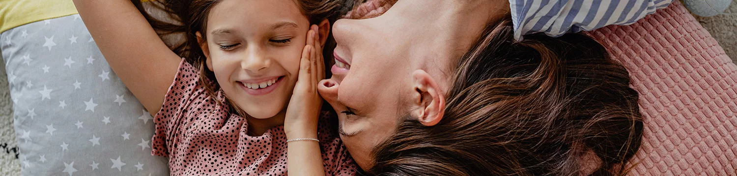 The mother has a gentle smile on her face, and the child is nestled close to her.